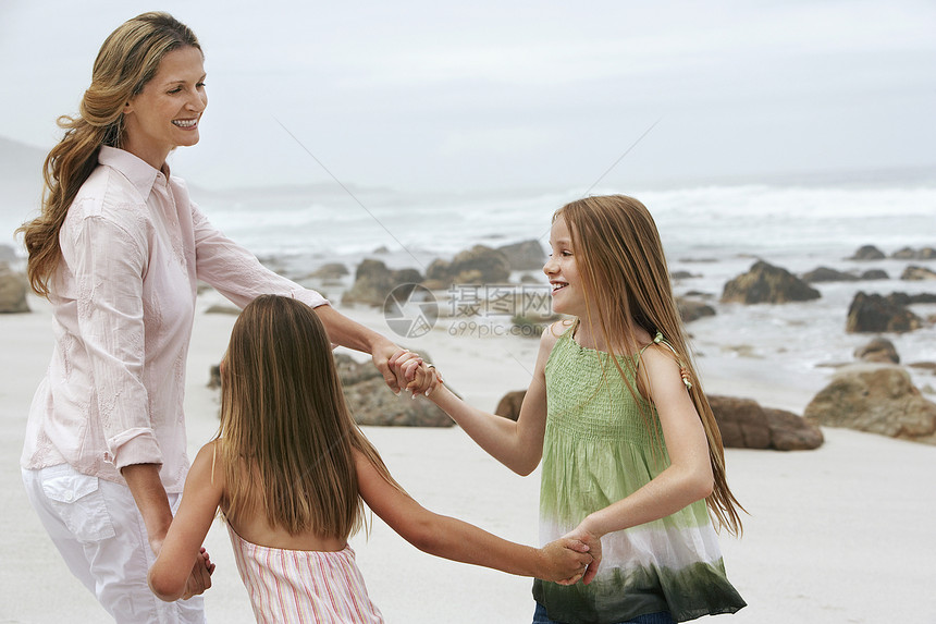 快乐的女人在玫瑰周围玩环 在沙滩上和女儿们一起玩图片