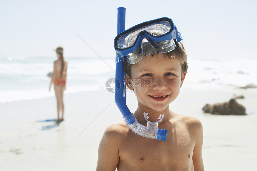 站在沙滩上时穿着潜水衣的可爱小男孩的肖像图片