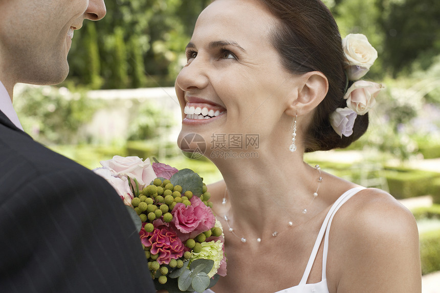 紧贴着微笑的新娘和花束 在花园里看着新郎图片