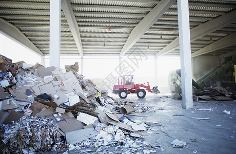 回收厂背景的废纸废物堆积物 装有挖掘卡车背景图片