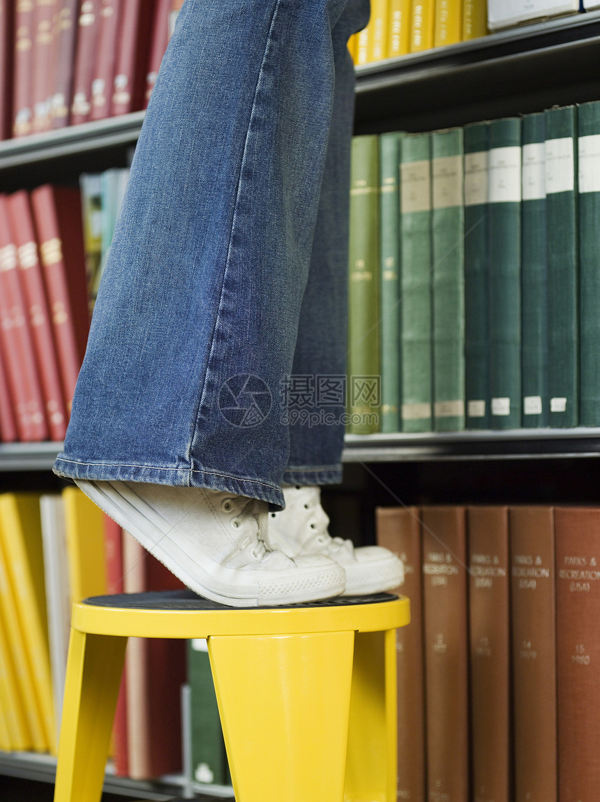 一名青年男子站在凳子上向图书馆求书的低层缝合图片