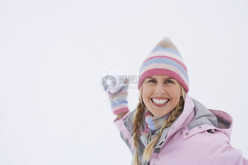 一个快乐的年轻女子在冬天扔雪球的肖像帽子成人闲暇女士衣服针织品乐趣恶作剧假期微笑图片