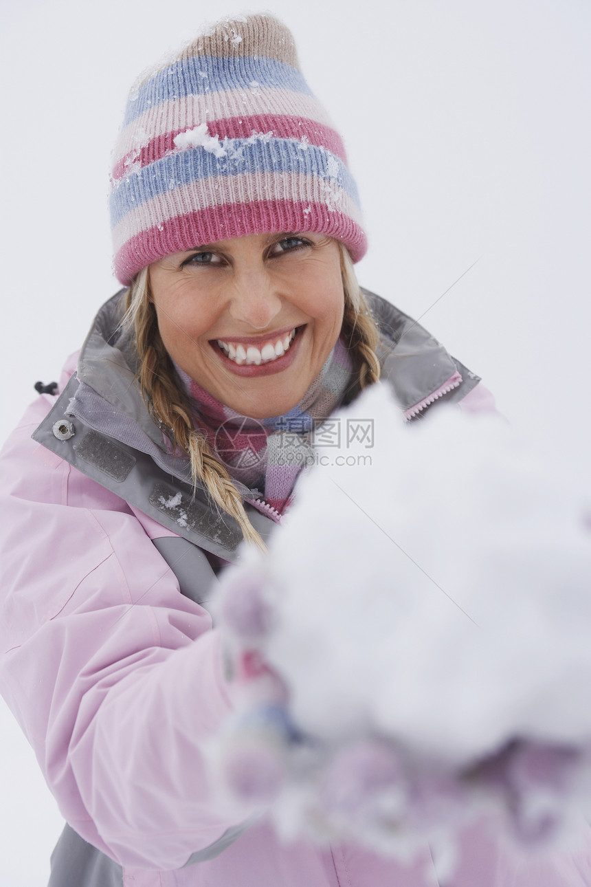 一个快乐的年轻女子在冬天 拿着雪球的肖像图片