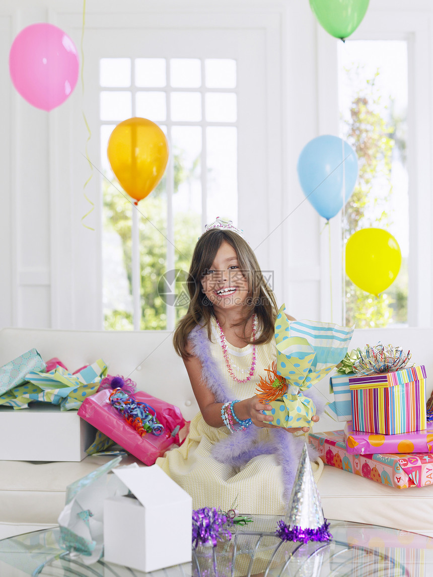快乐的年轻女孩 在家中开生日礼礼物享受皇冠青春期幸福气球孩子们好奇心房子庆典开幕式图片