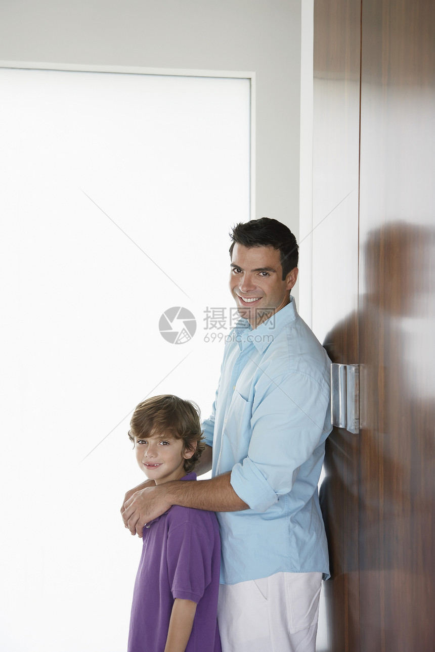 快乐的父亲和儿子的肖像 仰靠衣橱和微笑图片
