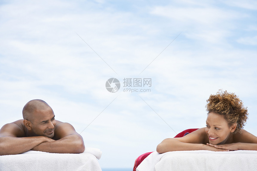 美籍非洲快乐情侣躺在按摩桌上对抗阴云的天空图片