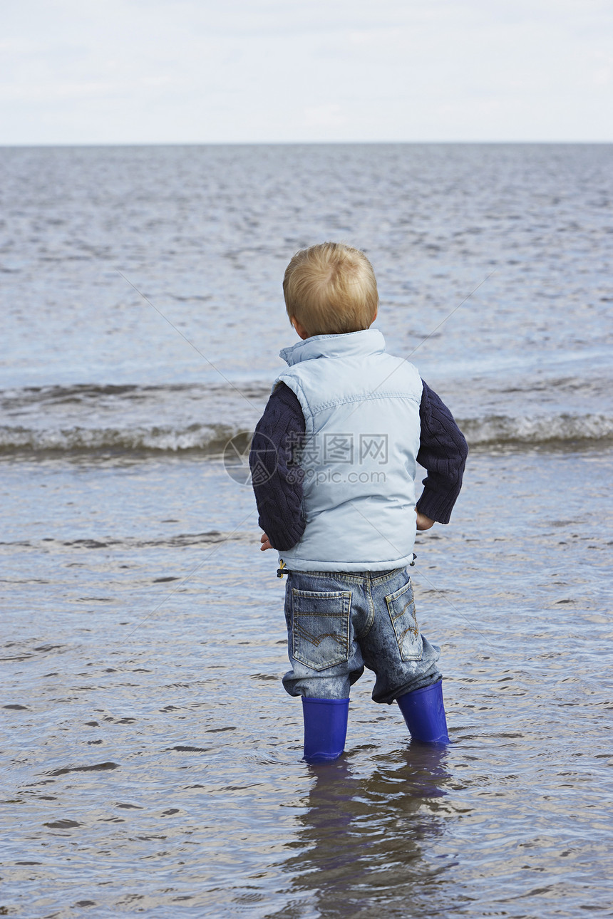 站在海洋中的年轻男孩的近视图片