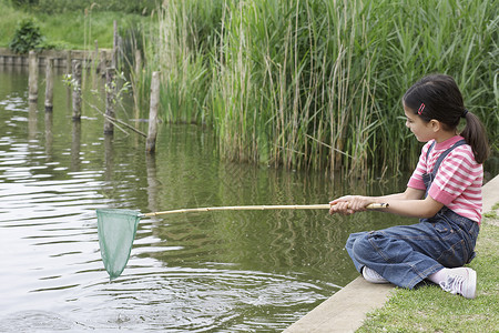 坐着钓鱼女孩整个快乐的年轻女孩在河边网钓鱼背景