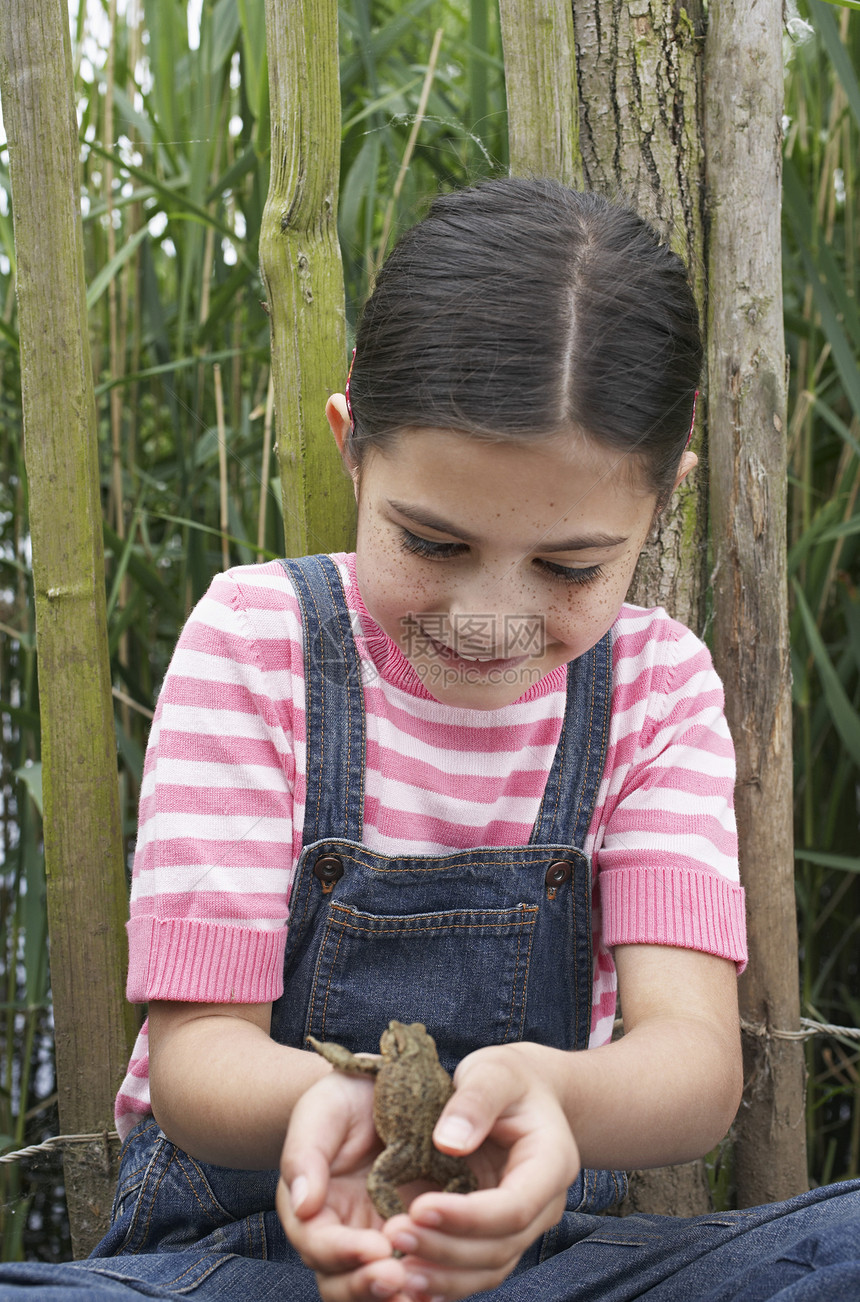 快乐的年轻女孩在栅栏前玩青蛙图片