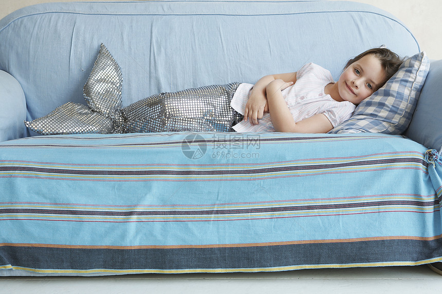 一个穿着美人鱼服装的年轻女孩的肖像 躺在家里沙发上图片