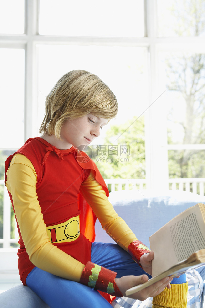 穿超人服装的年轻男孩 在室内阅读书图片