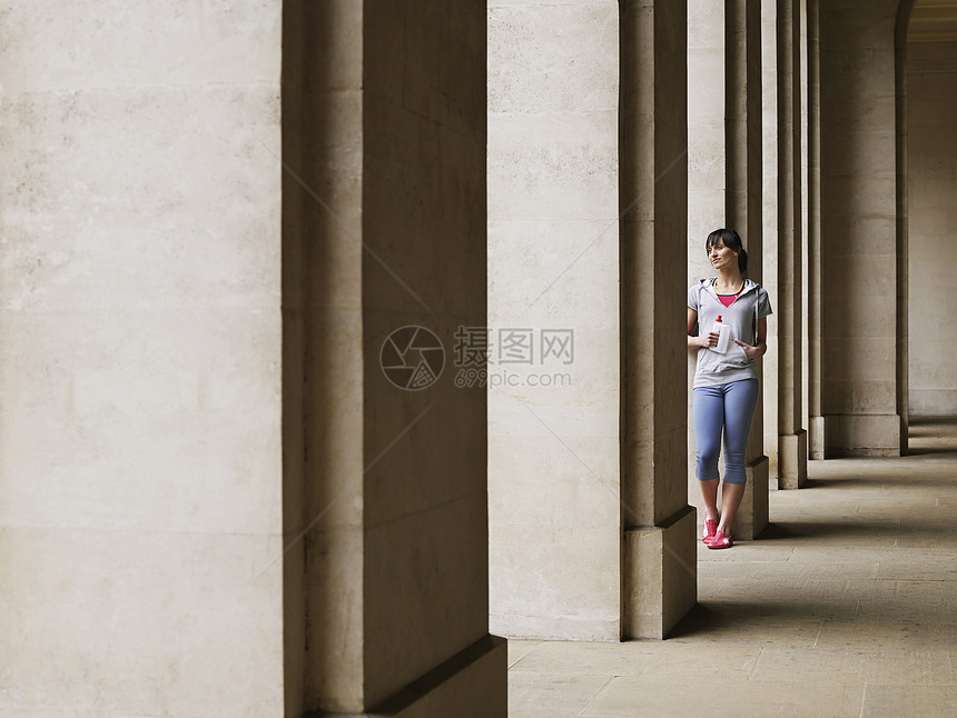 一名年青女子身高一整身 站在Portico的柱子上站立图片