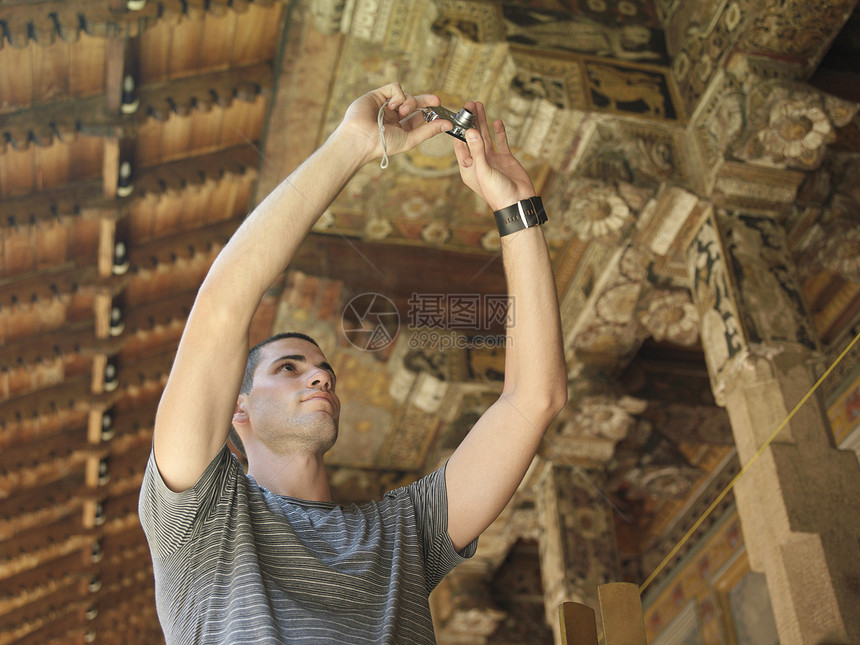 年轻男子拍摄寺庙木制细节照片的年轻人图片