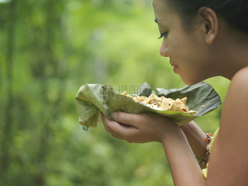 一位年轻女性的近视侧面 在青绿背景模糊的情况下在叶子上闻着食物的味道图片
