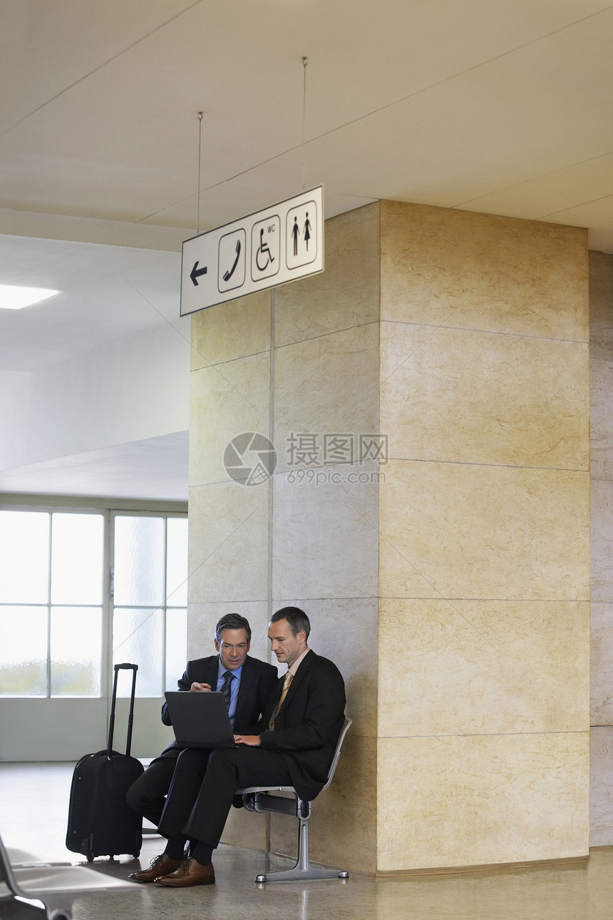在机场大厅使用膝上型电脑的两名商务人士男士飞机场工人笔记本大堂讨论中年办公室旅行商务图片