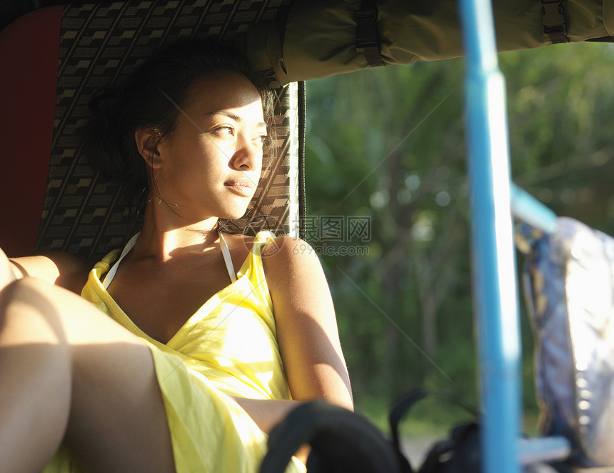 年轻混合种族妇女坐在人力车里 向外看黄色运输水平闲暇沉思女士女性思维阳光阴影图片