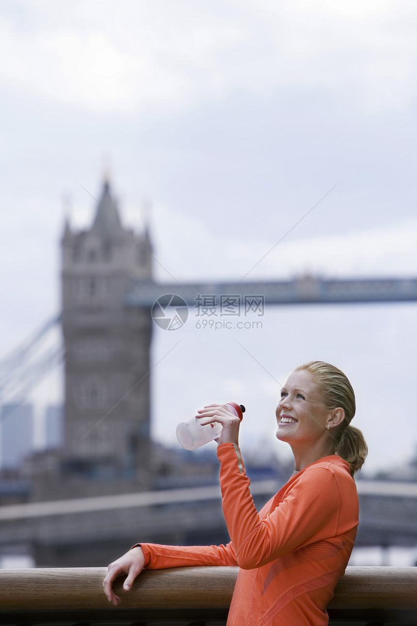 伦敦前的女子饮用水服装微笑女士塔桥前景城市成人位置休闲中年人图片