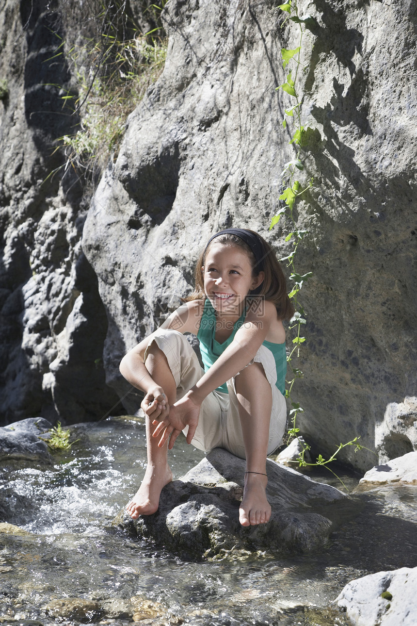 一个微笑的小女孩 坐在岩石上逐条溪流全长的肖像赤脚乐趣幸福女性孩子女孩头巾童年短发假期图片