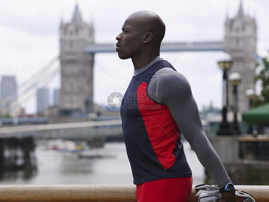 一位非洲裔美国人的侧视景 在英格兰塔桥前伸展一面城市男人拉伸运动员训练身体运动建筑学地标活力图片