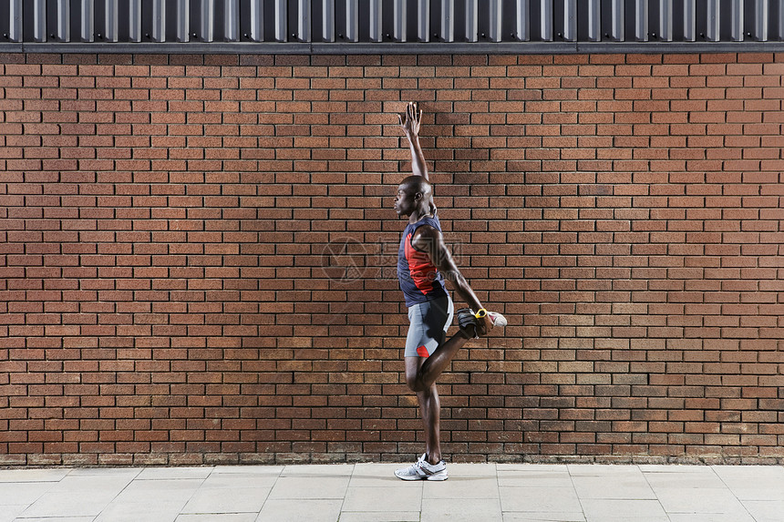 一个非裔美国人 站在砖墙的侧面全长的一面观图片