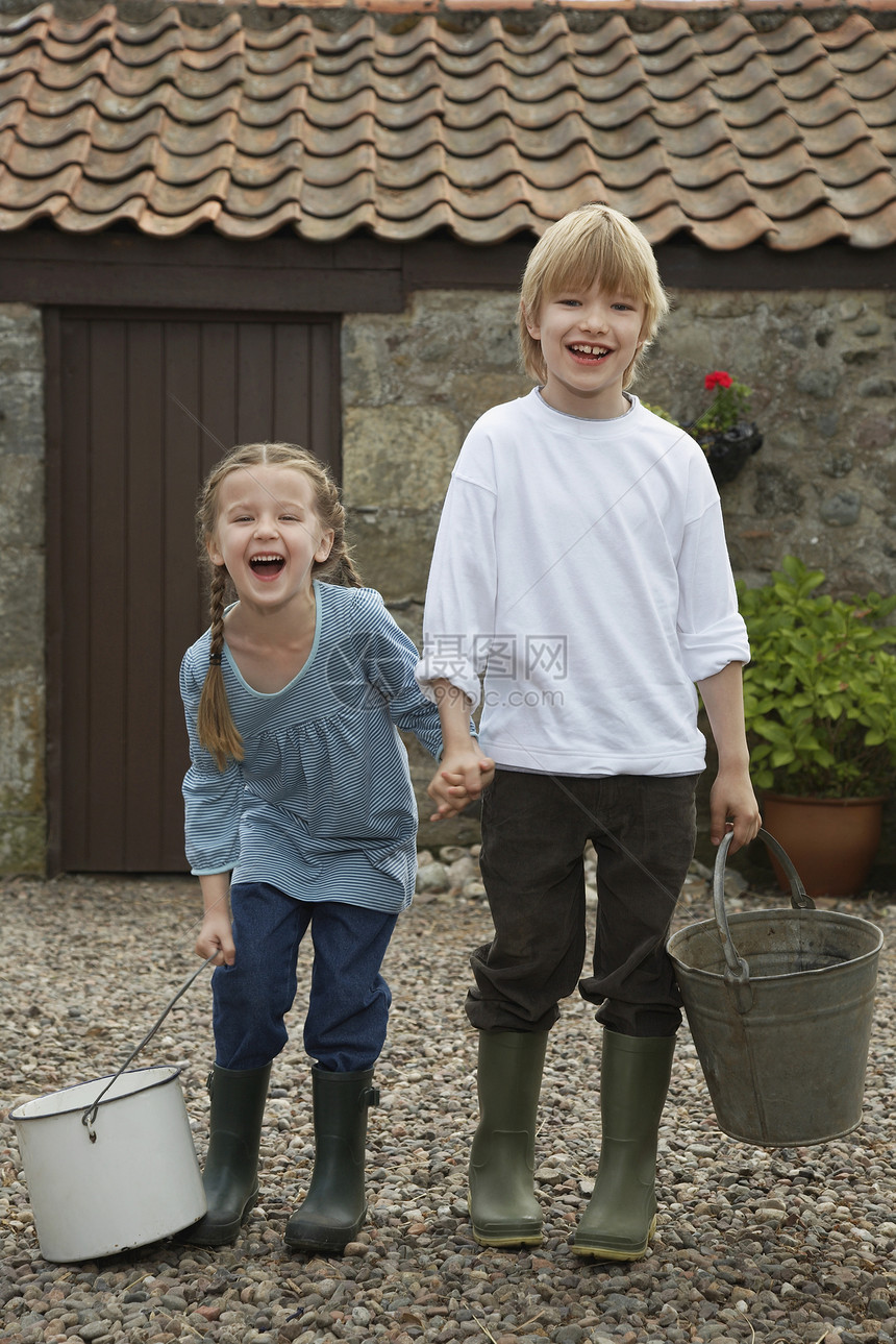 一个快乐女孩的全长肖像 和她的兄弟拿着马脚桶抱着水桶图片