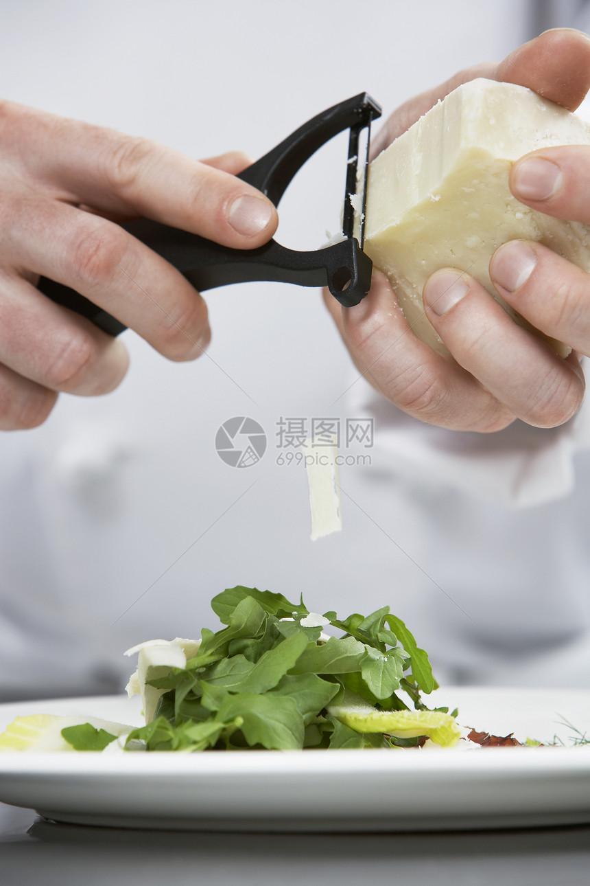 一个男厨师在沙拉上 烤起司的干酪图片