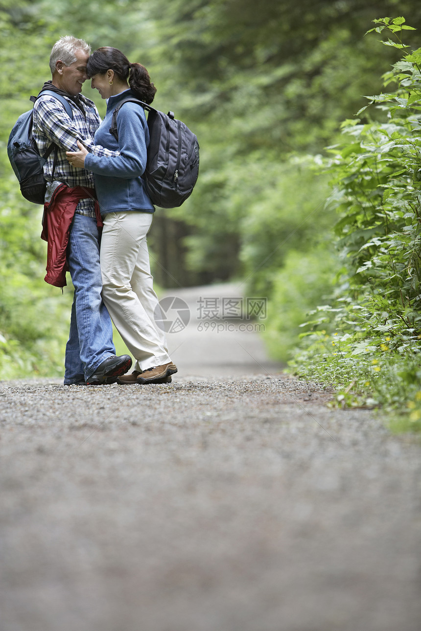 一对中年夫妇在森林公路上游荡的全长侧面图片