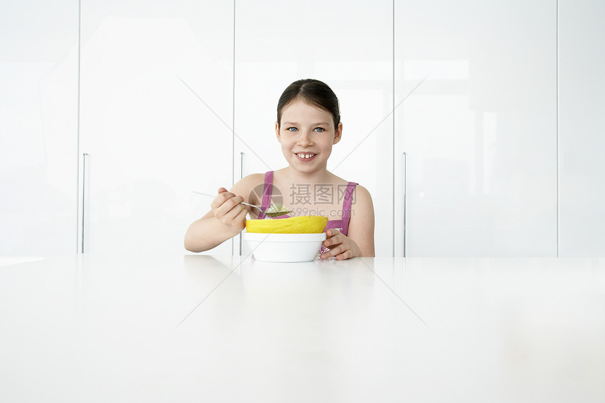 一个微笑的年轻女孩吃早餐的肖像图片
