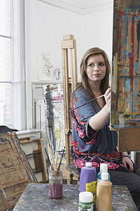 年轻女艺术家在艺术演播室的壁架上绘画背景图片