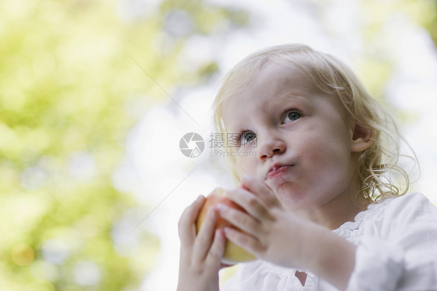一个金发女孩在户外吃苹果的近身肖像孩子视图孩子们水果水平低角度沉思闲暇食物童年图片