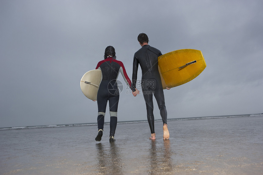 在海滩向海边行驶时看到一对夫妇与冲浪板相近的景象图片