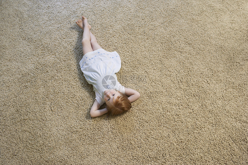 女孩躺在家地毯上的高角度肖像画图片