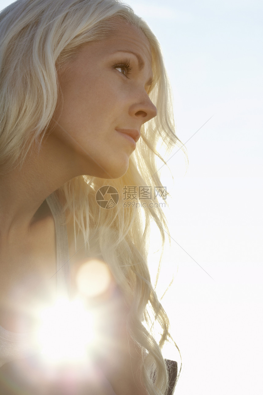 年轻女性对太阳的对抗 特写低角度视野阳光日落长发肩膀头肩一人成年沉思卷发头发图片