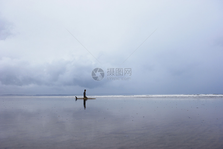 孤单冲浪者坐在浅水边风景的冲浪板上图片