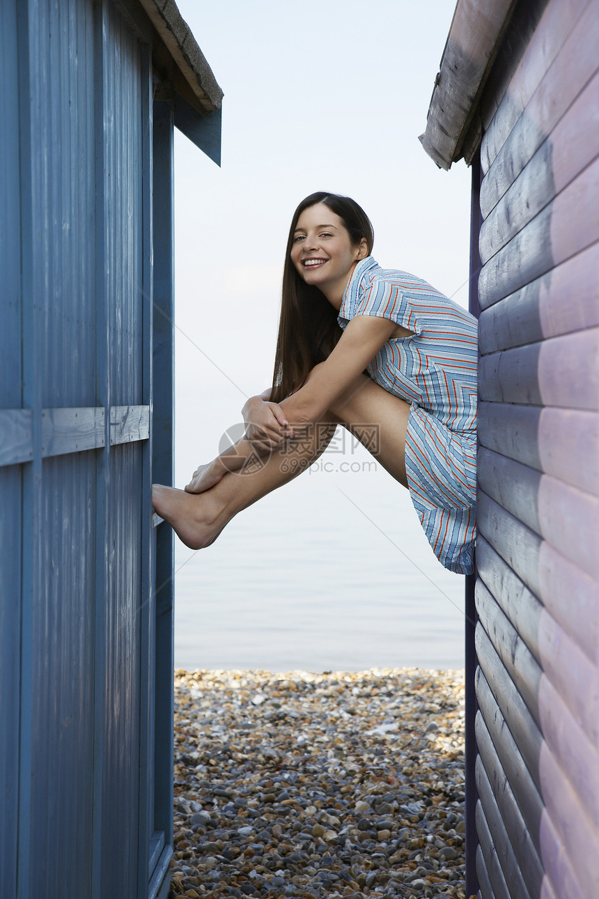 坐在沙滩别墅边上的快乐年轻女子的侧面肖像图片