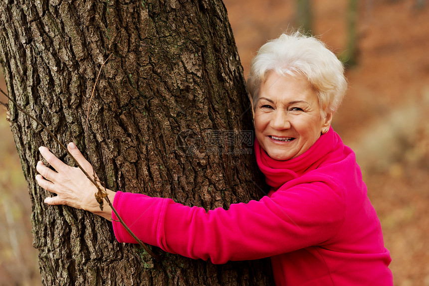 站在一棵树旁的一位深情的老太太的肖像祖母季节智慧乐趣树木活动女士农村公园退休图片