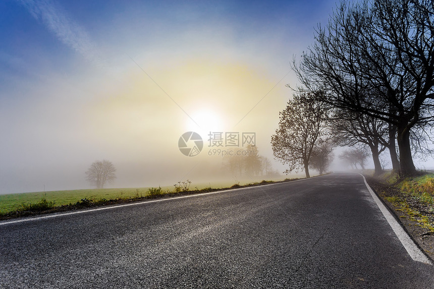 通往日出的农村迷雾道路沥青驾驶交通天气蓝色地平线薄雾太阳车道晴天图片