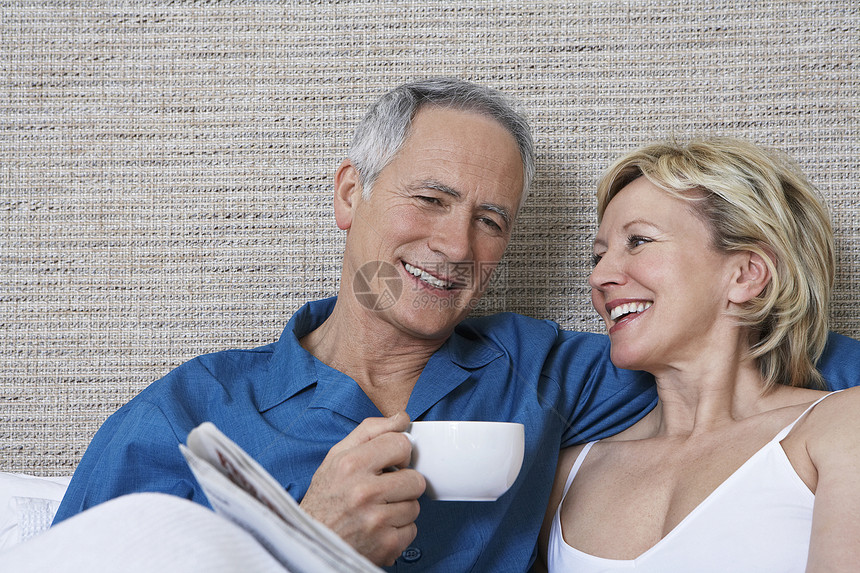 快乐的中年夫妇 床上有咖啡杯阅读报纸享受婴儿卧室男性房子夫妻咖啡男人幸福杯子图片