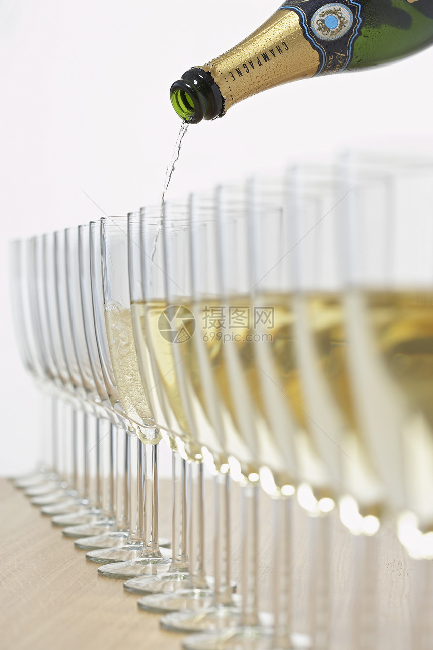 装满一排玻璃杯的香槟瓶 有选择性地聚焦图片
