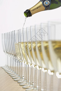装满一排玻璃杯的香槟瓶 有选择性地聚焦背景图片
