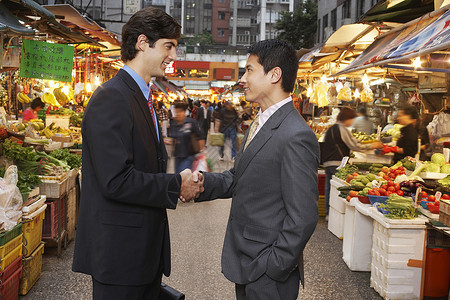 两个商务人士在街头市场上握手的男子背景图片
