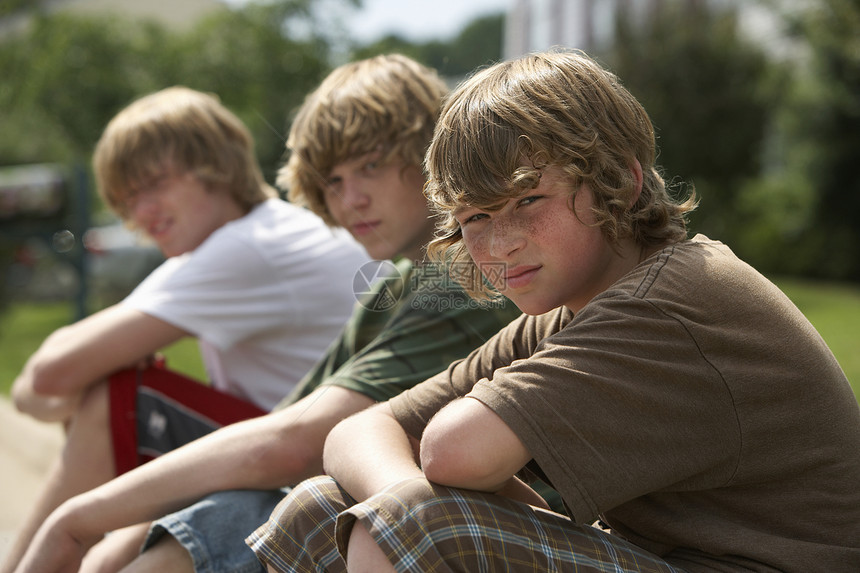 三名十几岁的兄弟(13至17岁)坐在街边路边画像上图片