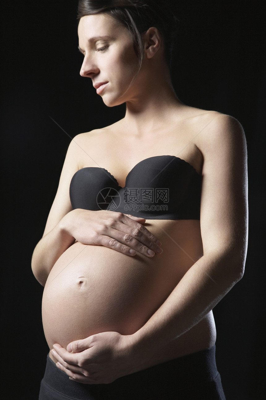 孕妇触摸腹部工作室镜头一人皮肤背景生长影棚人生眼睛内衣胸罩黑色图片