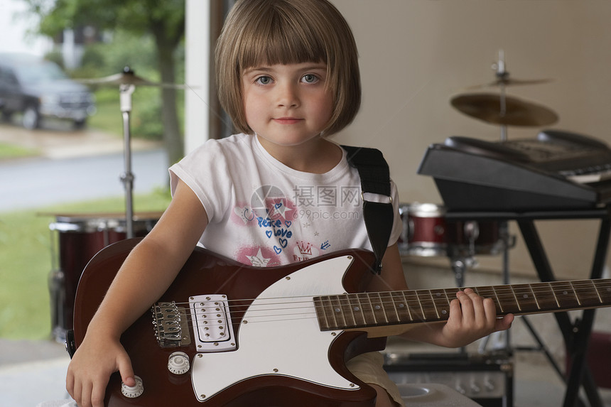 车库里拿着吉他可爱小女孩的特写肖像图片