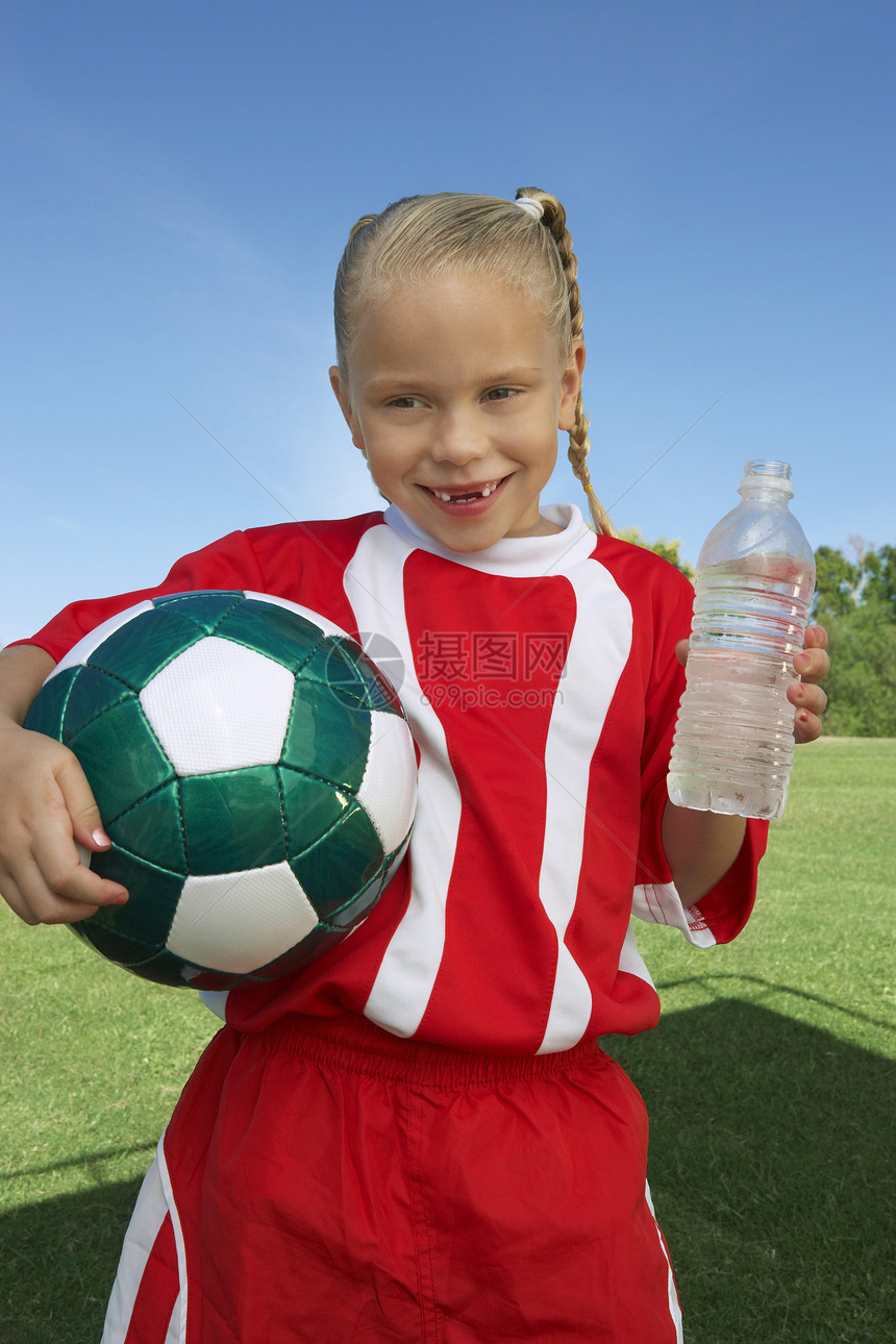 持有球和水瓶的年轻女子足球运动员的肖像图片