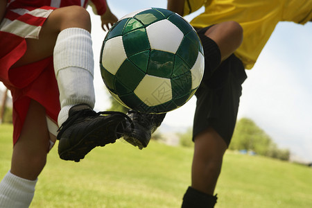 单足球素材两名多族裔足球运动员踢足球球的中区背景
