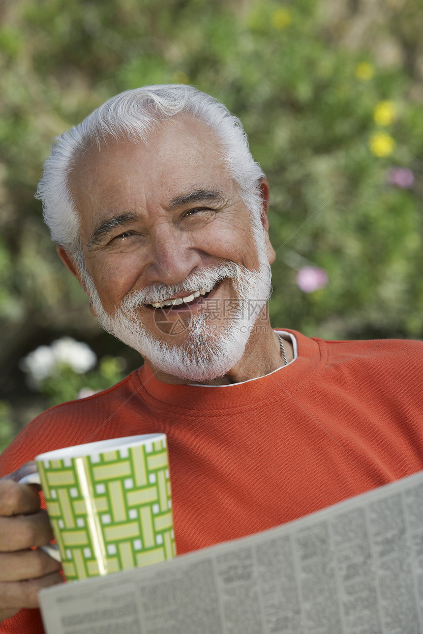 一个快乐的老人 拿着咖啡杯和报纸的肖像图片