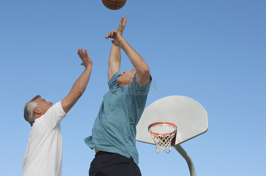 两名白人男性朋友在蓝天上打篮球图片