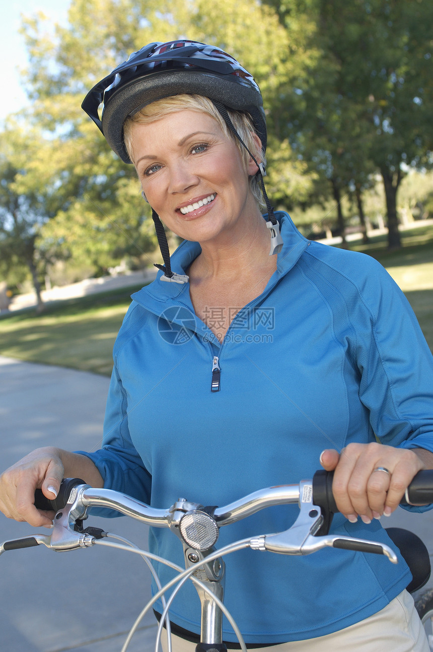 一名戴头盔 手持自行车把手栏的妇女的肖像图片