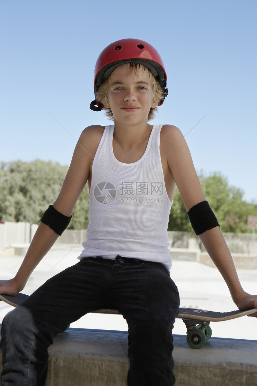 坐在滑冰公园滑板上的十几岁男孩的肖像图片